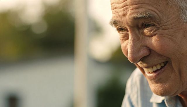 Smiling senior man shedding single tear in golden hour backyard portrait, emotional warmth