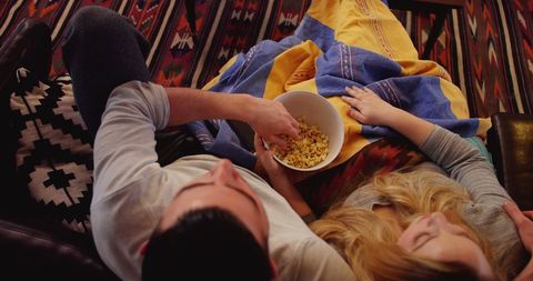 Couple relaxing on couch with popcorn at home
