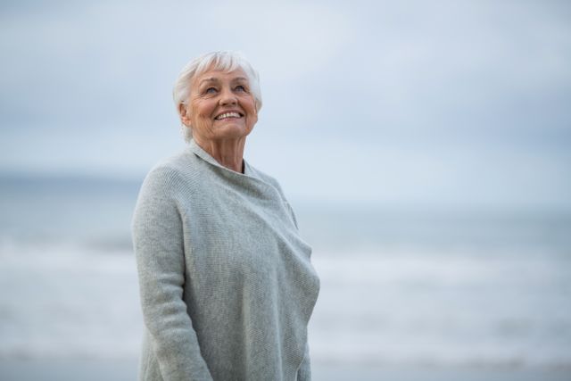 Senior woman standing on the beach - Download Free Stock Photos Pikwizard.com