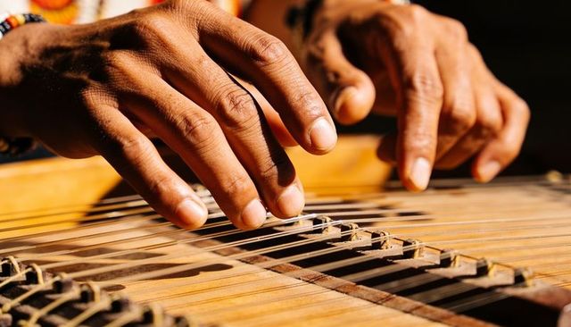 Closeup musician hands plucking qanun strings, tuning santur zither with finger technique