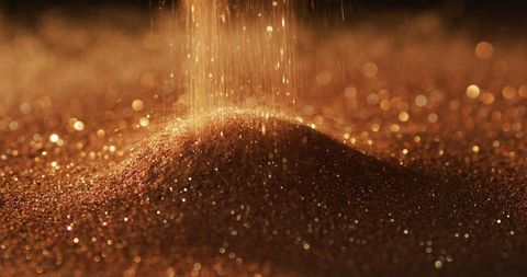 Shimmering gold glitter gems on dark background