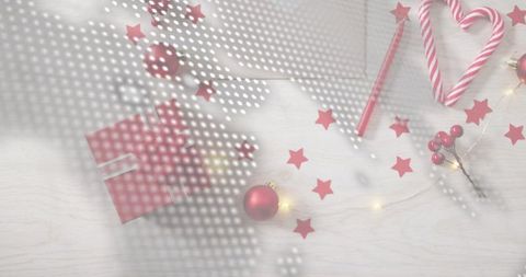 Festive red gift with ribbon, candy cane heart, red baubles and star confetti wood flatlay