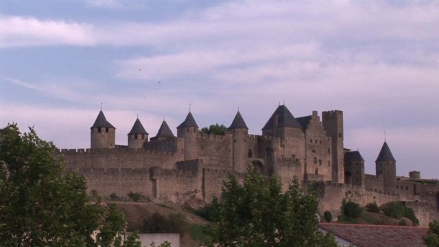 This stunning medieval castle in Carcassonne, France, features stone walls and multiple towers under a partially cloudy blue sky. Ideal for use in travel content, history materials, educational publications, and promotional materials aiming to attract tourists to this iconic French fortress.