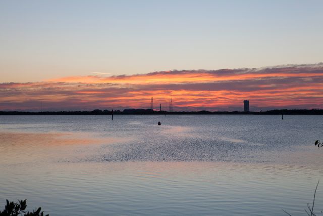 Sunrise over the Banana River at Cape Canaveral with Launch Complex 41 in the background. Ideal for depicting peaceful early morning scenes, aerospace engineering, NASA's space exploration efforts, and scenic landscapes by bodies of water.