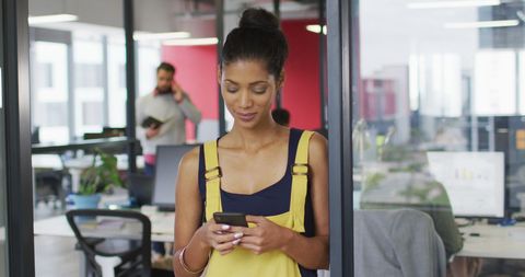 Confident Businesswoman Standing in Modern Office Using Smartphone