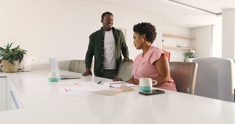 Diverse colleagues collaborate on office work with laptop and documents