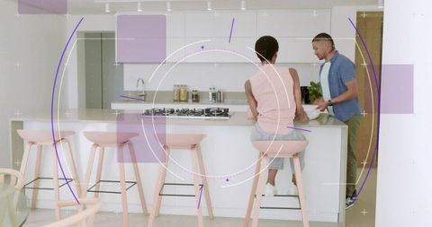 Couple cooking and chatting at modern white kitchen island with pink stools and cozy vibe