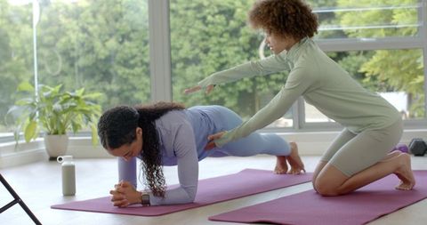 African american fitness instructor coaching forearm plank in bright home studio