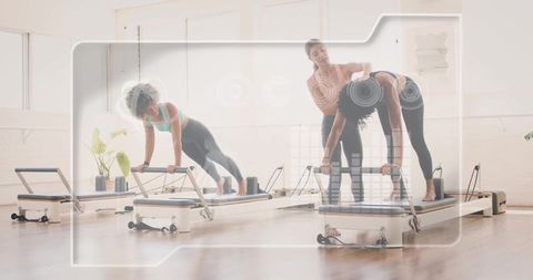 Pilates trainer guiding clients on reformers performing plank exercises in sunlit studio