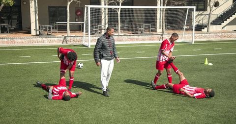 Teammates Practicing Soccer on Artificial Turf with Coach Guidance