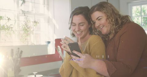 Joyful Caucasian Female Couple Embracing in Sunlit Kitchen