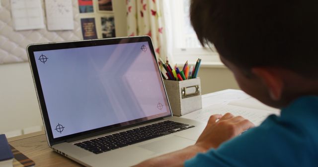 Child focused and engaged in online learning on laptop, sitting at desk in cozy home study room. Ideal for educational websites, online courses, homeschooling resources, tutoring services, and student-focused content.