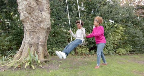 Joyful Motherhood: Mother Pushing Son on Garden Tree Swing - Download Free Stock Images Pikwizard.com