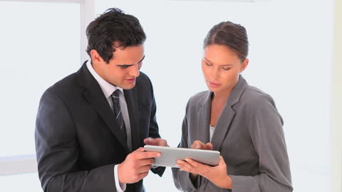 Professional Team Discussing Strategies on Tablet in Office