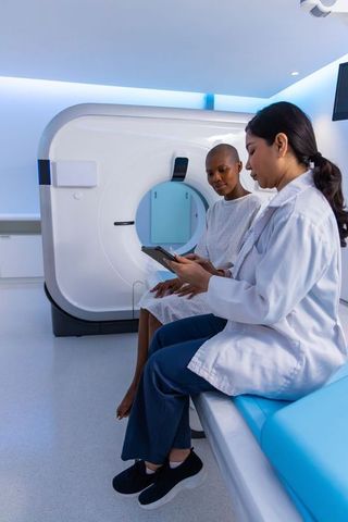 Clinician reviewing ct scan with diverse female patient in modern radiology room