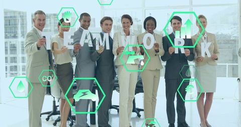 Corporate team holding TEAMWORK letters with green sustainability icons in bright office