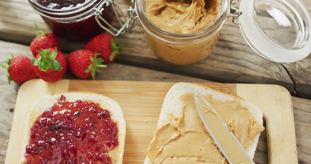 Peanut butter and jelly sandwich on wooden tray with milk and strawberries on wooden surface. food and nutrition concept
