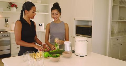 Two women preparing fresh vegetarian meal in modern kitchen