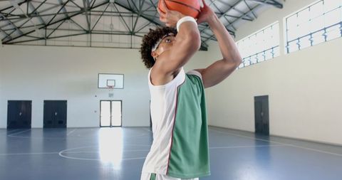 Young athlete practicing basketball shot in indoor gym