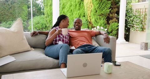 Afro-american couple enjoying coffee and laptop relaxation outdoors
