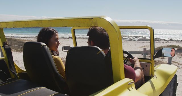 Couple enjoying a seaside adventure in a yellow dune buggy, driving along a scenic beachside road. Ideal for travel agencies, vacation promotions, adventure-themed advertisements, summer getaway articles, and romantic travel stories.