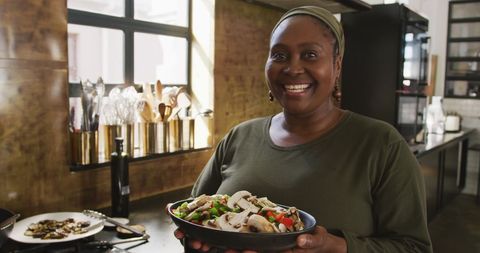 Senior Woman Smiling Holding Fresh Vegetable Dish in Kitchen