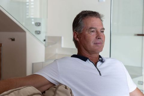 Middle-aged man sitting on sofa in modern home contemplating future and retirement