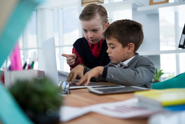 Kids as business executives discussing over laptop in office