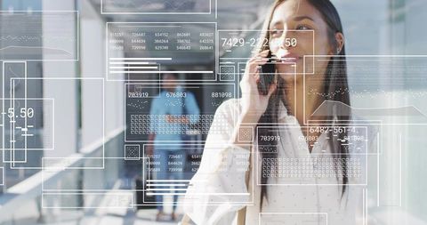 Businesswoman walking and talking on smartphone with digital HUD overlays in modern office
