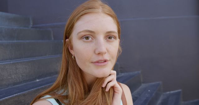 This image features a red-haired woman with a thoughtful expression, making eye contact with the camera. Suitable for use in lifestyle blogs, beauty and fashion websites, or social media posts emphasizing natural beauty and casual moments.