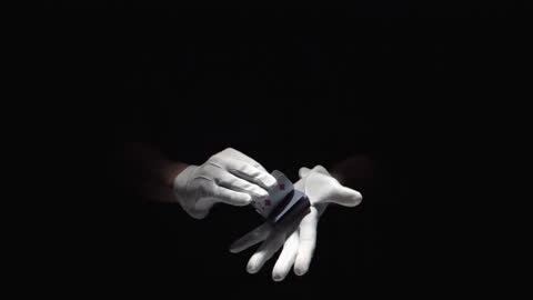 Gloved Hands Mastering Card Tricks in Darkness