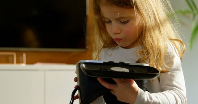Adorable girl looking at virtual reality headset at home. Girl holding virtual reality headset 4k