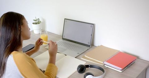 Focused Woman Working at Home with Laptop and Notebooks