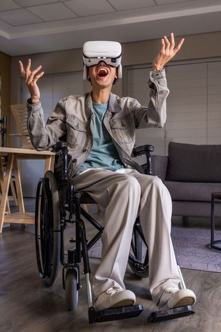 Young man in wheelchair enjoying immersive virtual reality gaming in living room