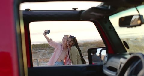 Friends taking selfie on beach getaway at sunset