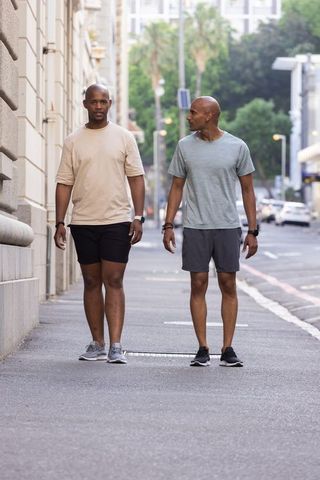 African american men walking on urban sidewalk wearing athletic wear and smartwatches
