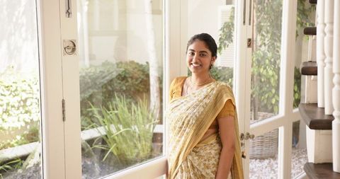 Smiling indian woman in traditional sari by bright window