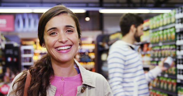 Smiling woman in grocery store aisle with male shopper in background - Download Free Stock Images Pikwizard.com