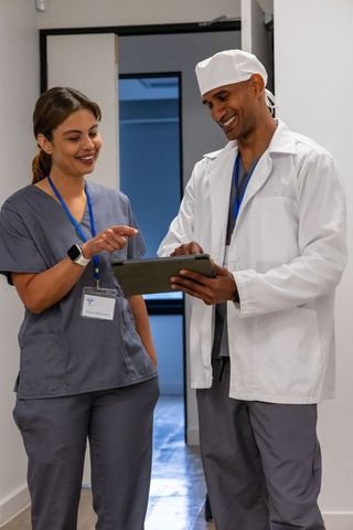 Medical staff reviewing tablet chart in hospital corridor, collaborating on patient care