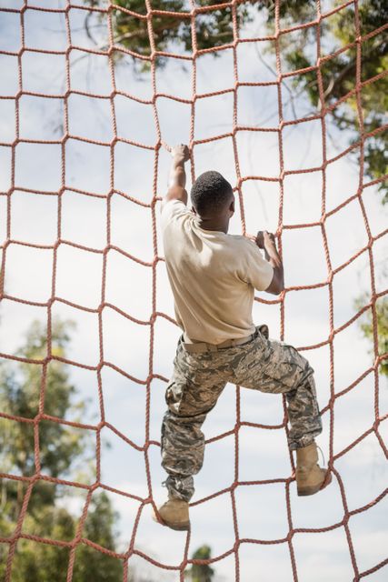 Military soldier climbing net during obstacle course in boot camp