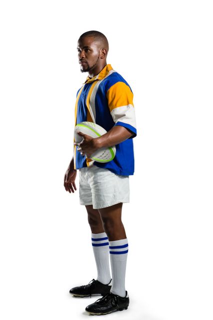 Side view of confident rugby player holding ball against white background