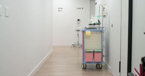 Wheeled medical supply cart standing in hospital radiology corridor with pink bins