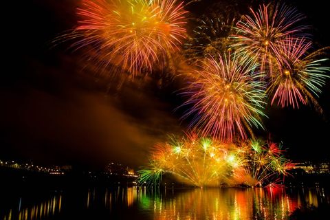 Vibrant fireworks exploding over city waterfront