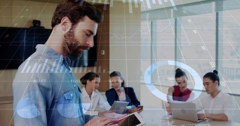 Bearded professional using tablet, team collaborating with interactive analytics dashboards