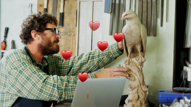 A craftsman in his workshop inspects a finely detailed bird sculpture with animated hearts showing his passion and love for the work. Ideal for use in materials involving artistic inspiration, craftsmanship showcases, and promotional content for art-related businesses or workshops.