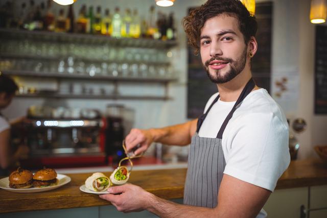 Portrait of waiter holding a plate of vegetable roll in cafÃ©
