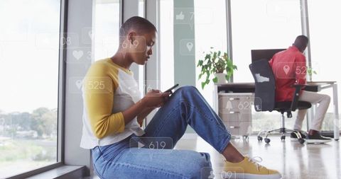 Young Professional Uses Smartphone in Modern Office with Social Media Graphics