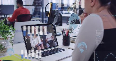 Joining remote meeting on laptop in modern open office with mature professional at desk