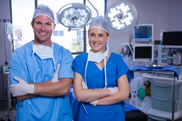 Portrait of male and female nurse standing with arms crossed in operation theater