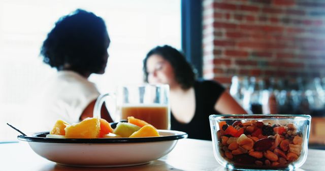 Two Women Conversing in Cafe with Snacks on Table - Download Free Stock Images Pikwizard.com